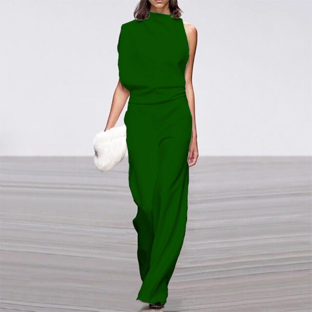 Frau in grüner ärmelloser Jumpsuit mit weitem Bein, hält weiße Clutch, elegantes Sommeroutfit.